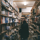 A man wearing glasses between two crowded bookshelves